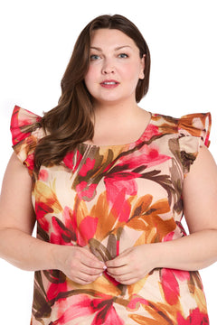 A woman with long brown hair models the Plus-Size Floral Party Dress: R&M Richards 4105W, a knee-length ruffle dress with a floral pattern, standing against a plain white background.