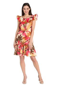 A woman models the Petite Short Print Party Dress: R&M Richards 4105P, a sleeveless floral dress with ruffled shoulders and a tiered skirt, featuring vibrant blooms for a playful yet elegant party look against a white background.