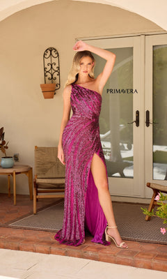 A woman stands on a porch in front of glass doors, wearing the glamorous Primavera One-Shoulder Long Beaded Prom Dress 4152—a magenta, sequined gown with a thigh-high slit. The word "Primavera" appears on the door behind her.