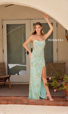Woman in the Beaded-Print Designer Prom Dress: Primavera 4156, featuring beaded details and a thigh-high slit, poses on a porch near a door with wooden chairs and a plant in the background.