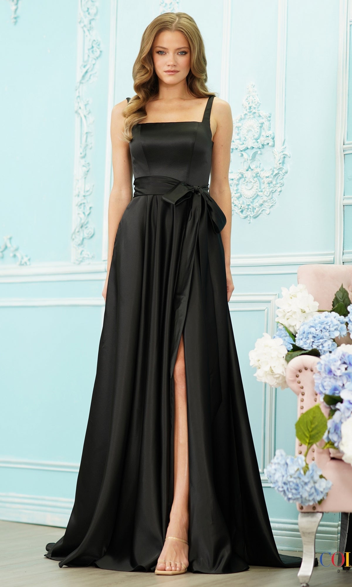 Colors Dress 4157 black satin A-line prom dress featuring a square neckline, a bow sash at the waist, and a thigh-high front slit.