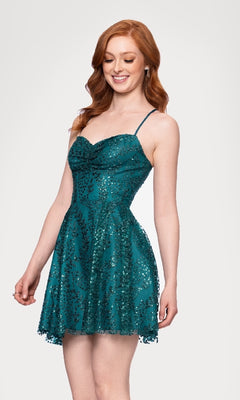A woman with long red hair wears the Short Teal Glitter Hoco Dress: Blondie Nites 4159BN, featuring thin straps and a fitted sequined bodice, standing against a plain white background.
