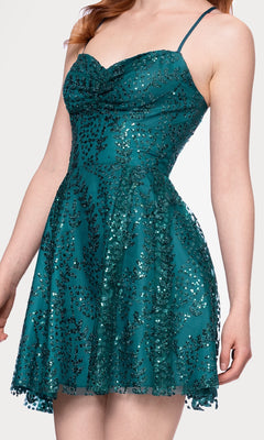 A woman wears the Short Teal Glitter Hoco Dress: Blondie Nites 4159BN, featuring thin straps, a sleeveless design, and a flared skirt.