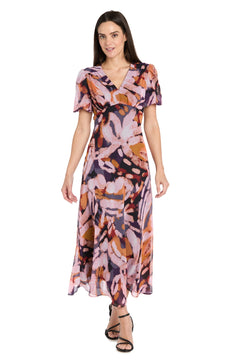 Woman modeling the R&M Richards 4161 Short Sleeve Print Party Dress with an abstract pink, purple, and orange pattern against a white background. Ideal for weddings or any semi-formal event.