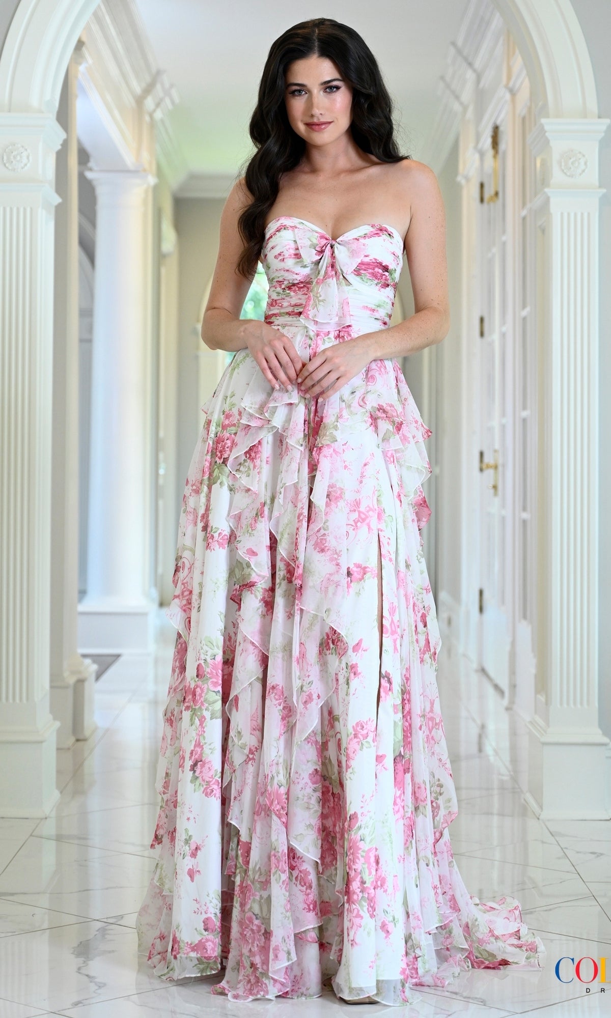 Pink strapless floor-length floral chiffon Colors Dress 4171 prom dress with a tiered ruffled skirt and a front tie bodice.