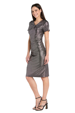 A woman models the R&M Richards 4177 short metallic cocktail dress with black high-heeled sandals, smiling as she stands against a white background.
