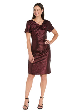Woman smiling in the R&M Richards 4177 short metallic cocktail dress, a shimmery burgundy knee-length style with short sleeves, paired with black high-heeled sandals—set against a white background.