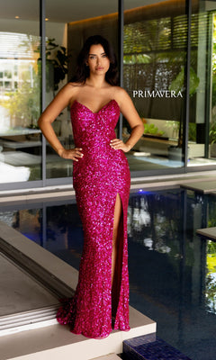 A woman in the Primavera Strapless Long Sequin Prom Dress 4192 with a thigh-high slit stands by an indoor pool, the "PRIMAVERA" logo in the background showcasing this glamorous designer gown for any formal event.