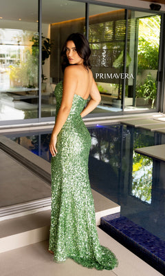 A woman wearing the Primavera Strapless Long Sequin Prom Dress 4192 in green stands beside an indoor pool, looking over her shoulder. The word "PRIMAVERA" appears nearby.