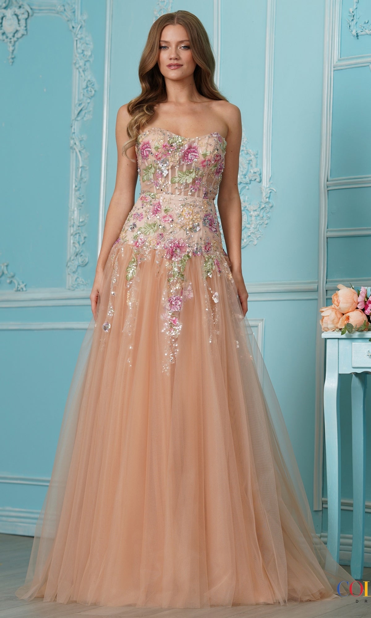 Long Prom Dress: Colors Dress 4199, a strapless champagne-colored floor-length tulle prom dress featuring a bodice with floral embroidery and sequin details.