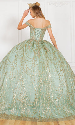 A woman wearing the Quinceanera Dress 4201 by Cinderella Couture—a pale green ball gown with gold embellishments and a crown—stands on a wooden floor, elegantly facing away in a refined room.