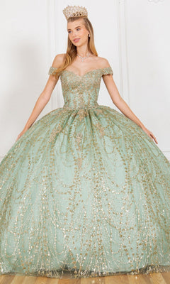 A woman wearing the Quinceanera Dress 4201 By Cinderella Couture in sage, an off-the-shoulder ball gown adorned with gold embellishments and paired with a crown, stands in front of a white wall.