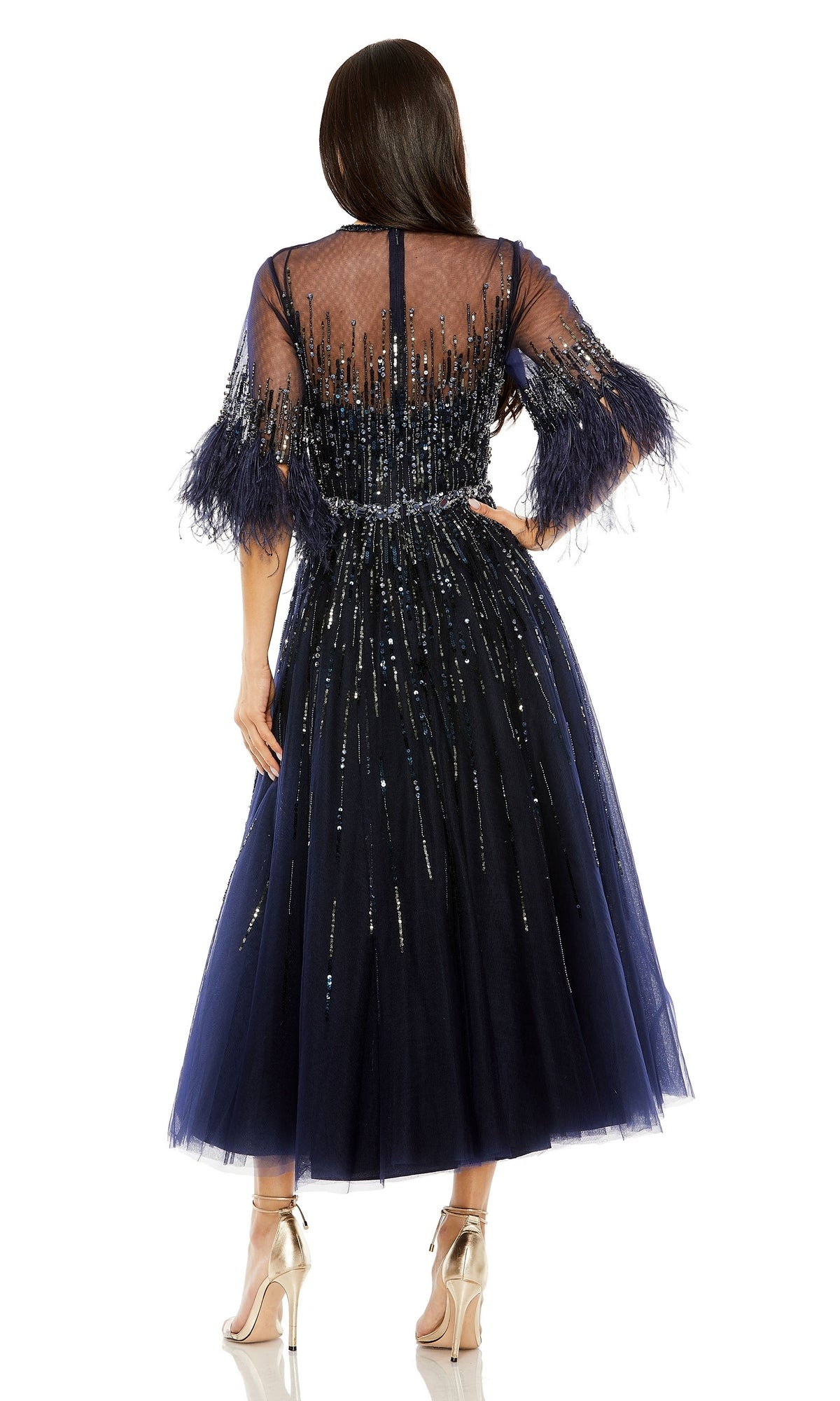 A woman stands with her back to the camera wearing the Mac Duggal Navy Midi Wedding-Guest Dress 42097, featuring sheer embellished fabric, sequin details, and feathered sleeves.