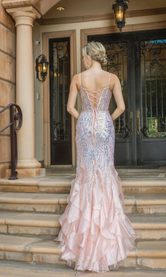A woman in the Long Sequin Mermaid Prom Dress with Ruffles 4221, featuring pale pink sequins and ruffled details, stands on stone steps with her hair in an updo, facing ornate double doors.