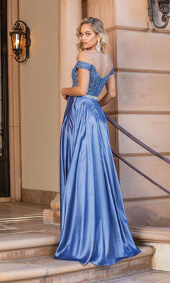 A woman stands on stone steps by a beige building, glancing over her shoulder in the Embroidered Off-Shoulder Long Prom Dress 4222A, featuring a sheer embroidered bodice.