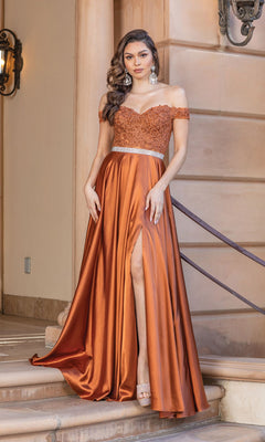 A woman stands on stairs wearing the Embroidered Off-Shoulder Long Prom Dress 4222A, featuring a sheer embroidered bodice, embellished belt, satin skirt with high slit, and statement earrings.