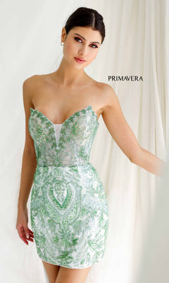 A woman in the Strapless Short Beaded Hoco Dress: Primavera 4226, featuring green and silver sequin details, stands before a light curtain with "PRIMAVERA" in the background, highlighting this stunning party dress.