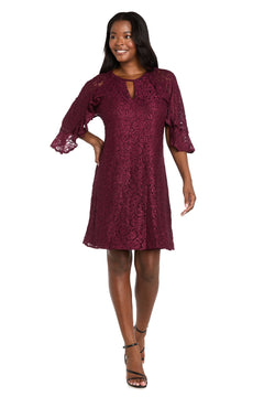 A woman wearing the R&M Richards 4226 Short Lace Semi-Formal Dress with a knee-length a-line silhouette, burgundy glitter lace, three-quarter bell sleeves, and black strappy heels stands against a white background.