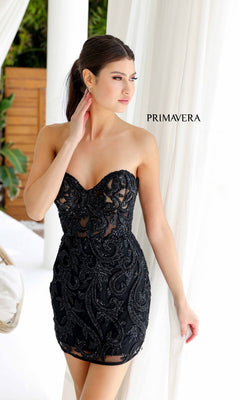 A woman wearing the Strapless Beaded Short Hoco Dress: Primavera 4227 poses by white curtains, gazing to the side. The word "PRIMAVERA" is displayed in the background.
