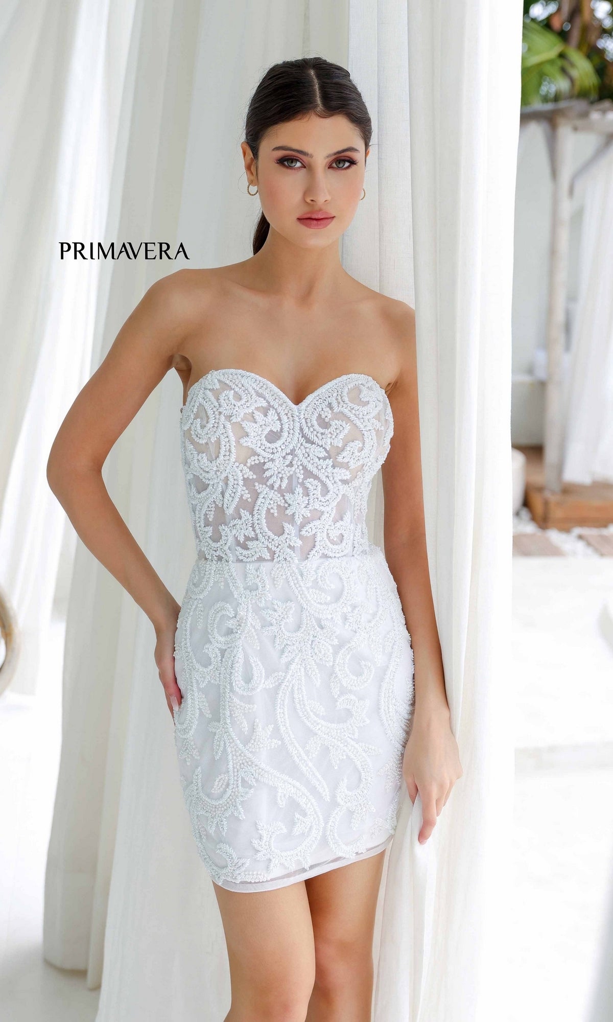 A woman models the Strapless Beaded Short Hoco Dress: Primavera 4227 indoors before white curtains, with 