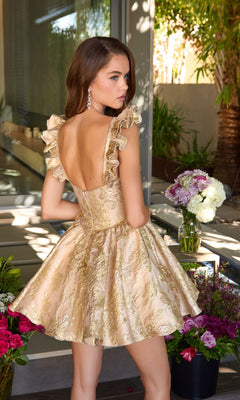 A woman in the Ava Presley 42395 short gold floral jacquard dress with ruffled straps stands indoors by a table with vases of flowers, glancing over her shoulder.