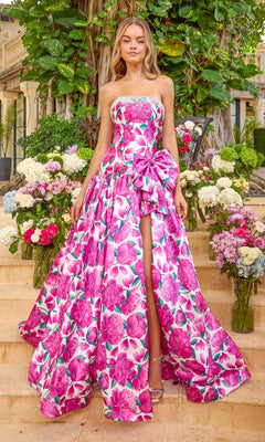 A vibrant pink strapless, floor-length Ava Presley 42459 floral prom dress with a side bow and high leg slit, modeled on stone steps among flower arrangements.