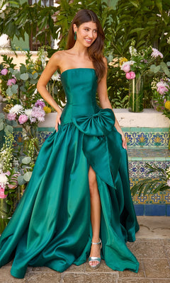 A woman wearing an emerald green Ava Presley 42477 strapless prom ball gown featuring a large side bow and a high front slit.