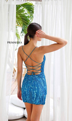 A woman in the Short Homecoming Dress 4250 by Primavera—blue, beaded, with a lace-up back—stands near white curtains and green plants, hand on her head and facing away. "PRIMAVERA" is displayed on the left.