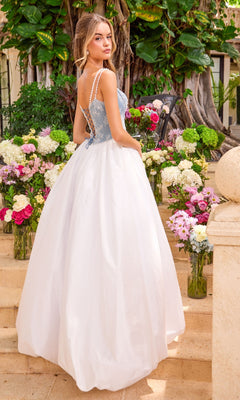 The back view of a blue and white Long Prom Dress: Ava Presley 42519 featuring a lace corset bodice and full skirt, positioned on stone steps in front of flower arrangements.