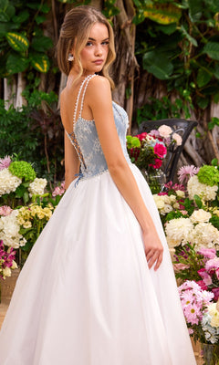 A woman wears an Ava Presley 42519 long prom dress featuring a blue lace corset-style bodice with pearl-beaded straps and a flowing white skirt.