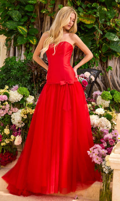 Long Prom Dress: Ava Presley 42521, a strapless red floor-length gown with a fitted bodice, a drop waist featuring a small bow, and a full tulle A-line skirt, standing among colorful flowers.