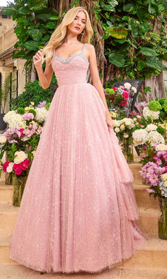 A woman wearing a floor-length, beaded pink sweetheart Ava Presley 42526 prom dress with rhinestone-trimmed straps, standing among vases of flowers.
