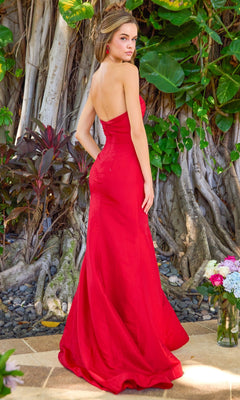 A woman in a red Ava Presley 42538 long prom dress with a detachable overskirt stands in front of large tree roots.