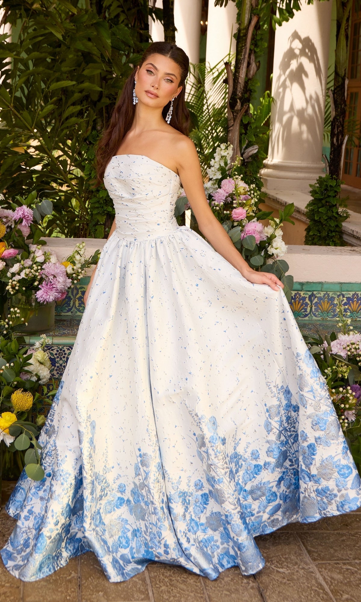 A strapless, floor-length Long Prom Dress: Ava Presley 42540 ballgown with a white bodice and a blue floral print pattern that fades from the hem upward.