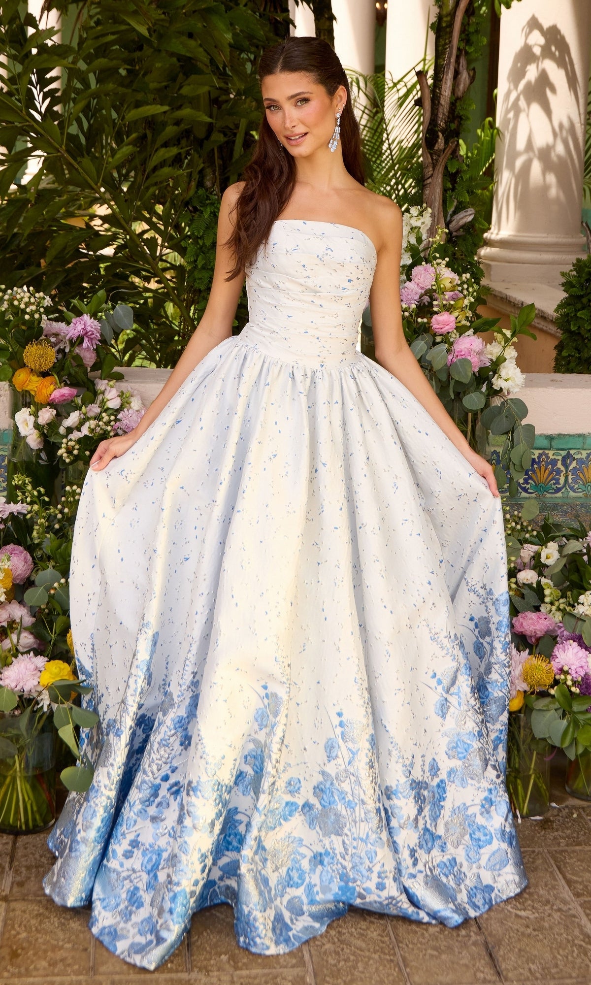 Ava Presley 42540 white strapless floor-length ball gown featuring a blue floral pattern at the hem.