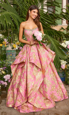 A woman wears a pink, strapless Ava Presley 42541 ballgown with gold floral patterns and a beaded neckline while holding a bouquet of pink peonies.