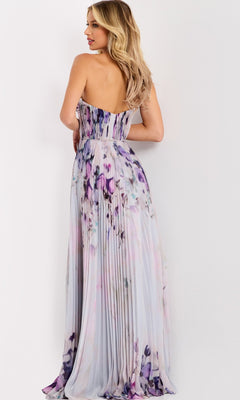 A woman models the Jovani 42564 Long Prom Dress, featuring a strapless floral design in purple and lavender hues, with her back to the camera against a white background.