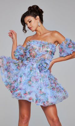 A woman poses against a plain background wearing the Jovani Puff-Sleeve Short Print Hoco Dress 42573, featuring blue floral patterns and ruffled details.