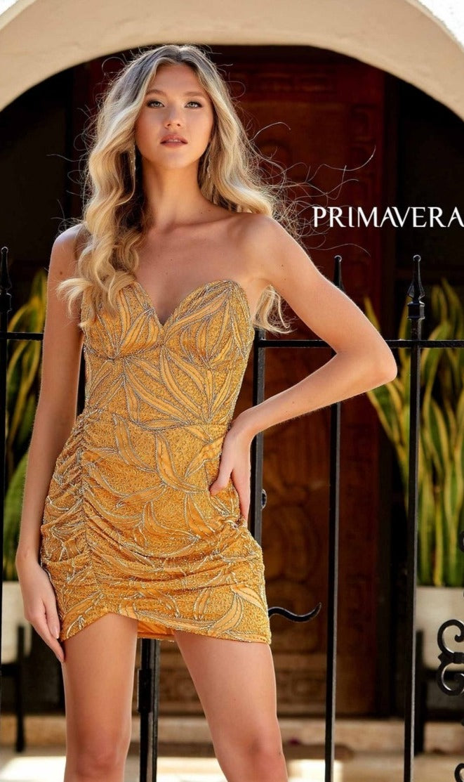 A woman in the Primavera 4259 Strapless Beaded Mini Hoco Dress with a sweetheart neckline stands before a dark wooden door and black iron gate.