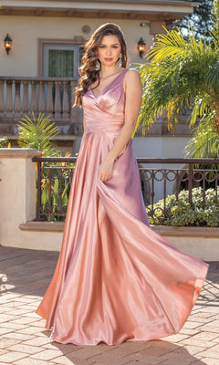 A woman wears the Wrap-Bodice Long A-Line Prom Dress with Corset, a sleeveless, floor-length, shiny pink gown under $200, standing outdoors by a railing with greenery and a building behind her.