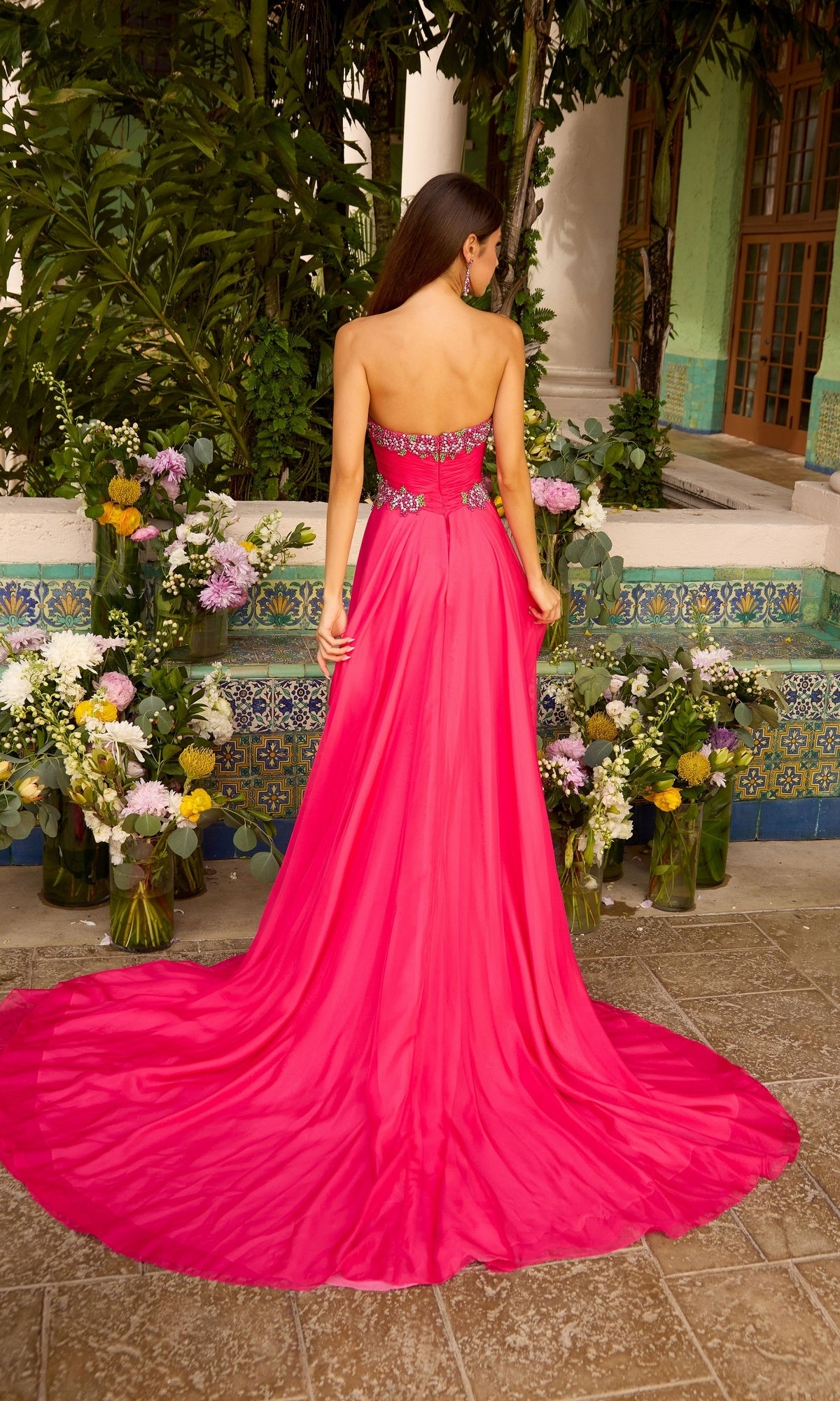 A person seen from behind wearing an Ava Presley 42650 strapless, fuchsia floor-length gown with a beaded bodice and a full skirt with a train.