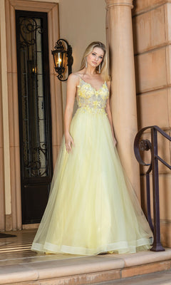 A woman stands on steps by a doorway, wearing the Long A-Line Tulle Prom Ball Gown with Flowers 4276—an elegant light yellow dress featuring 3-D floral designs and thin straps.