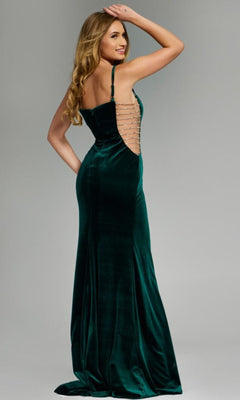 A woman models the Jovani 42783 long prom dress in dark green velvet, showcasing its open back with horizontal straps and embellished sheer sides, while standing and looking over her shoulder against a neutral background.