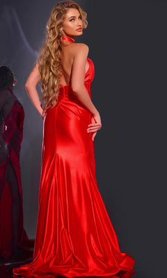 A woman with long wavy blonde hair poses in the floor-length, backless Jovani 42822 prom dress featuring a thigh-high slit, against a dark background with her side profile reflected in a mirror.