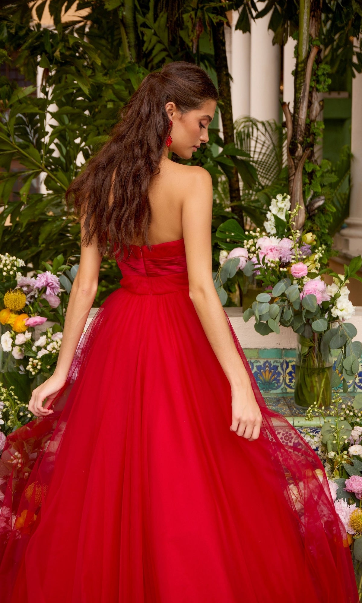 A person seen from behind wears a red, strapless, floor-length Ava Presley 43045 prom dress with a voluminous tulle skirt.