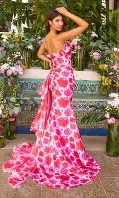 A woman wears an Ava Presley 43057 floor-length, strapless, pink floral mermaid prom dress with a ruffled neckline and draped back detail.