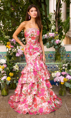 A woman wears a Long Prom Dress: Ava Presley 43081, a strapless, floor-length mermaid gown with pink and red floral embroidery and a tiered, ruffled skirt.