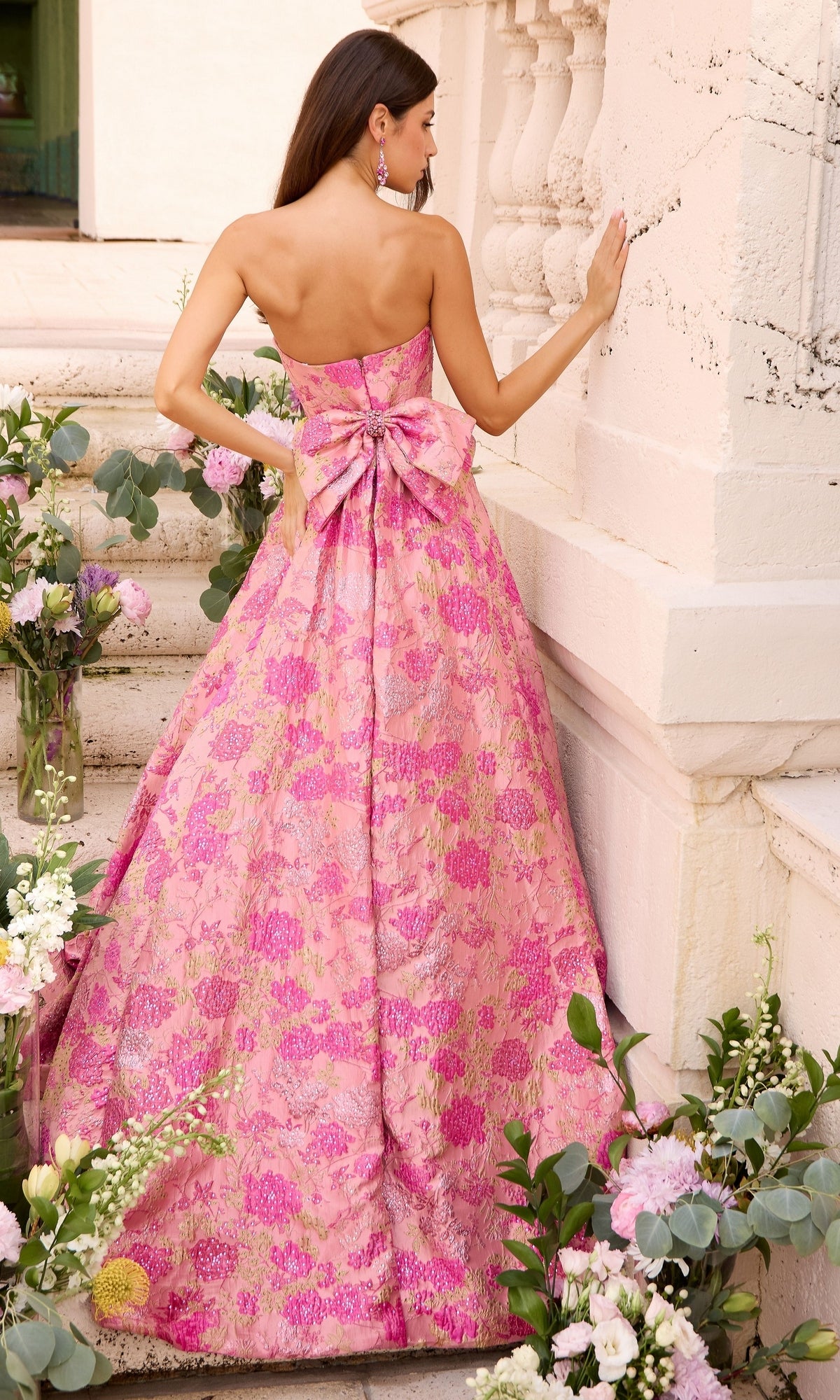 Back view of the Long Prom Dress: Ava Presley 43082, a strapless, floor-length pink floral ball gown featuring a large bow at the waist.