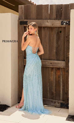 Woman in the Primavera 4309 Cut-Out Strapless Sequin Prom Gown, light blue with beaded details and a lace-up back, posing outdoors by a wooden gate.