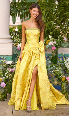 A strapless yellow Long Prom Dress: Ava Presley 43103 ball gown featuring a jacquard floral pattern, a large bow at the hip, and a high leg slit.
